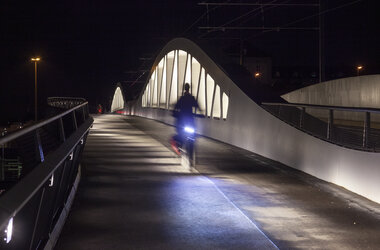 Fahrradfahrer fährt in der Nacht über die Brücke