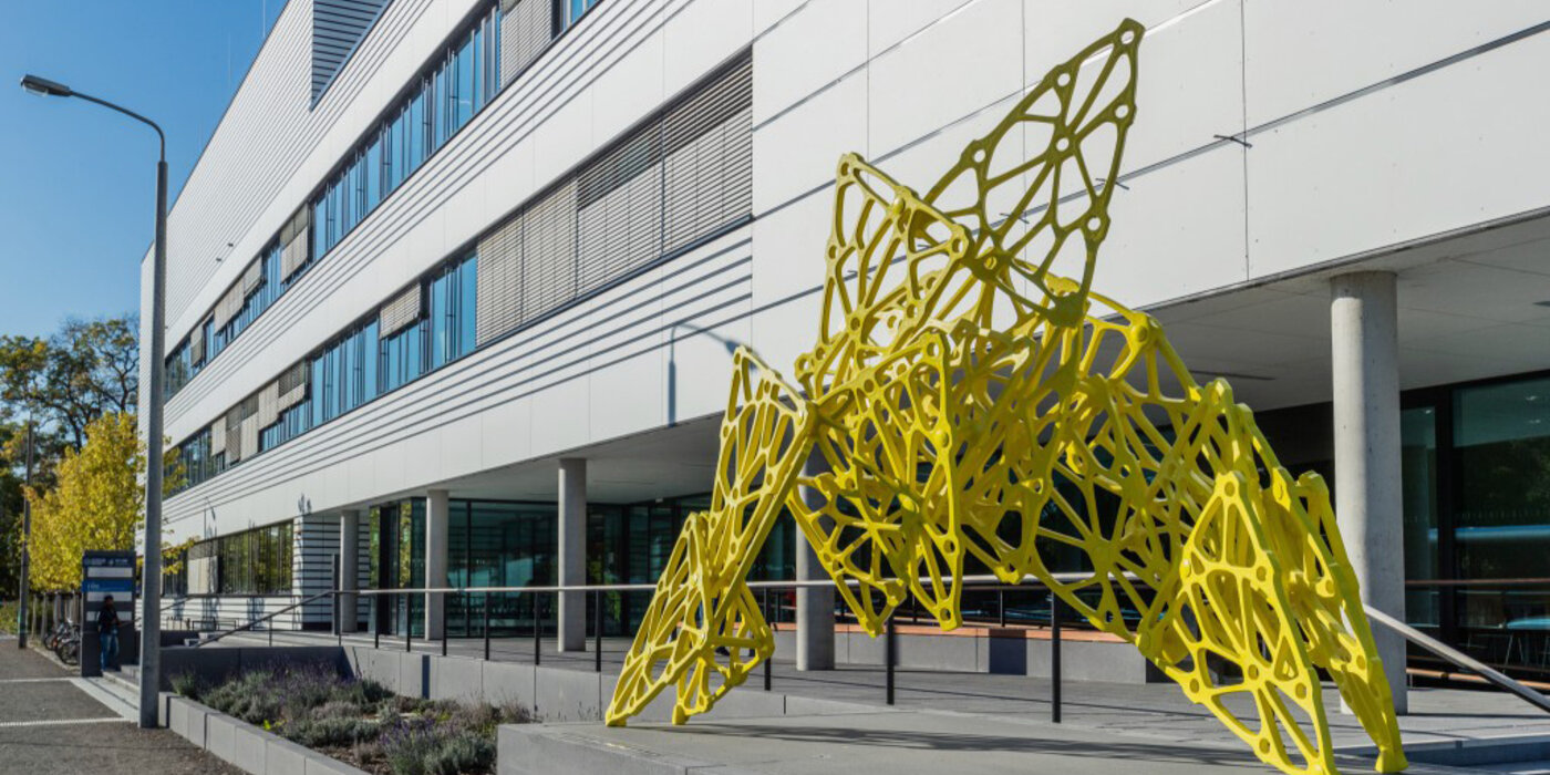 Gelbe Skulptur im Vordergrund und weißes Gebäude im Hintergrund