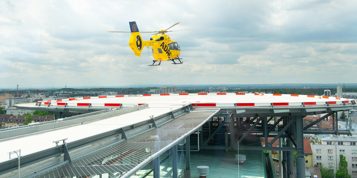 Gelber Hubschrauber fliegt vom Landeplatz ab