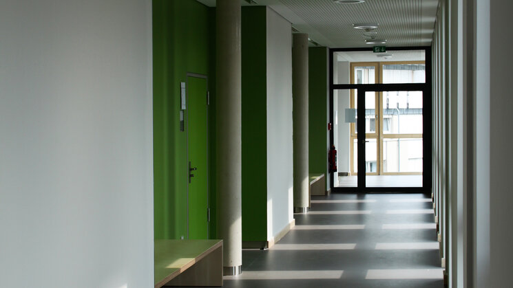 Schulflur mit weißen Wänden und grünen Türen