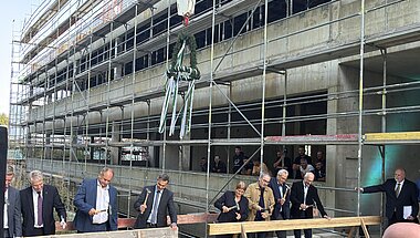 Traditioneller Nageleinschlag beim Richtfest mit Richtkranz.  Von links: Dr.-Ing. E. h. Thomas Reiter, Abteilungsleiter für Raumfahrt und Sicherheit im Bundesministerium für Forschung, Technologie und Raumfahrt; Dirk Hilbert, Oberbürgermeister der Landeshauptstadt Dresden; Falk Reinhardt, Technischer Geschäftsführer des Staatsbetriebs Sächsisches Immobilien- und Baumanagement; Juliane Schmidt, Kaufmännische Direktorin des IFW Dresden; Jan Gerken, Kanzler der TU Dresden; Prof. Dr. Bernd Büchner, Wissenschaftlicher Direktor des IFW Dresden, und Prof. Dr. Matthias Vojta, Sprecher des Exzellenzclusters ctd.qmat.