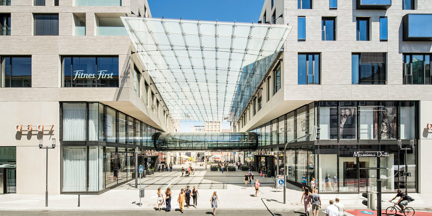 Zwei Gebäude mit Verbindungsstück und Fußgängern