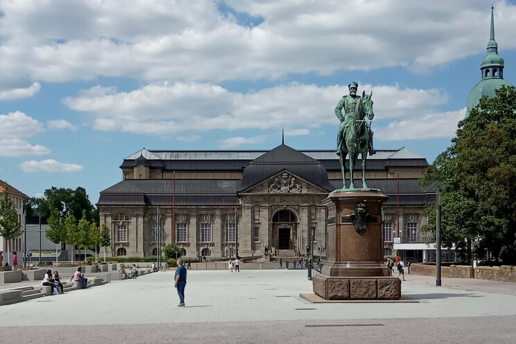 Friedensplatz mit Museum im Hintergrund und im Vordergrund eine Statue