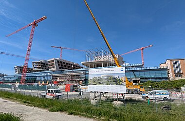 Blick auf Neubau mit Kränen und Bauschild